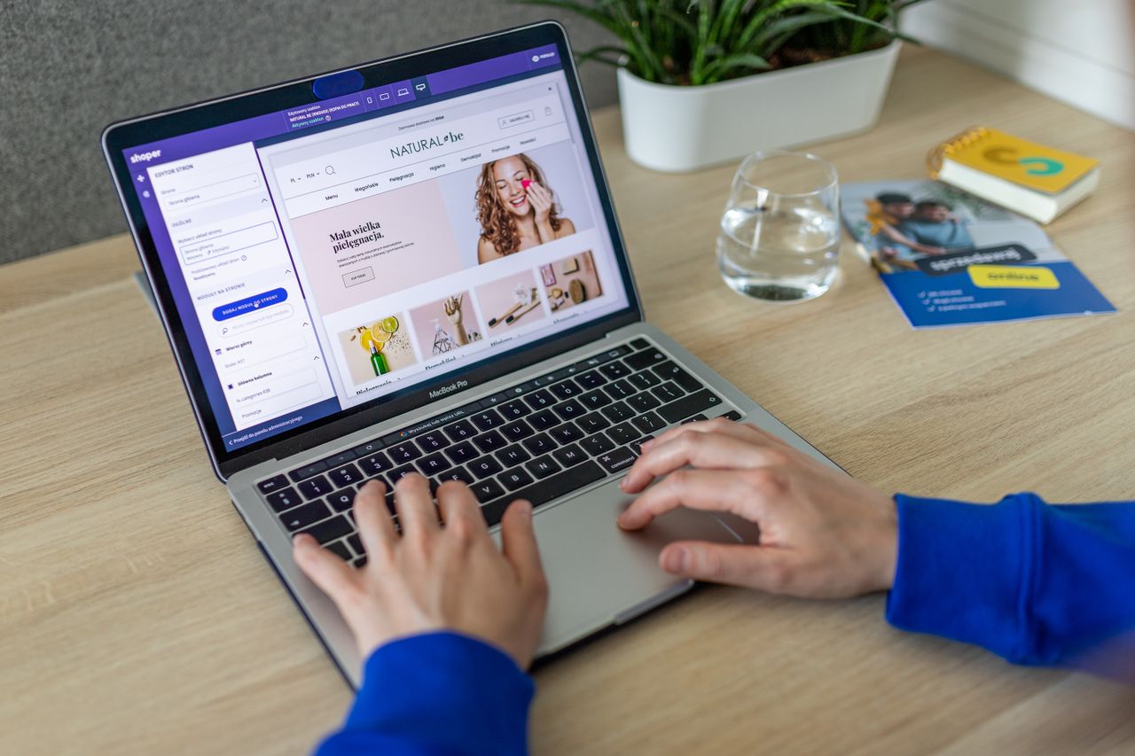 about-us Hands typing on a laptop showing an e-commerce website in a modern office setting.